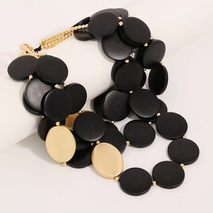 Collier bohème à plusieurs rangs avec disques en bois noir et or mat sur un support