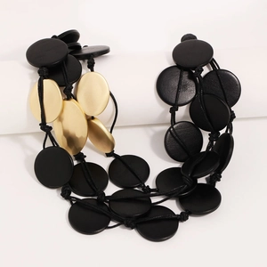 Multilayer long wooden necklace in black and gold finish on a minimalist display