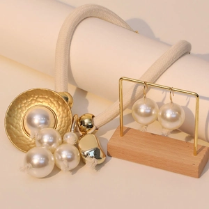 Detail of elegant faux pearl necklace set with woven rope and hammered gold metal discs