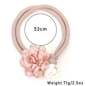 Detail of pink fabric flower curtain tieback with faux pearl and rhinestone accents