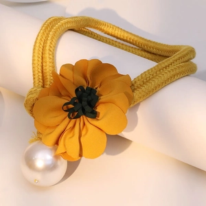 Detail eines gelben Haargummis mit Stoffblume und einer großen künstlichen Perle