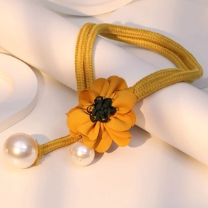 Detail der gelben Stoffblumen-Halskette mit eleganten Perlen auf weißen Sockeln