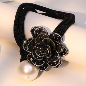 Close-up of black fabric rose hair tie with shimmering rhinestones and a large pearl bead