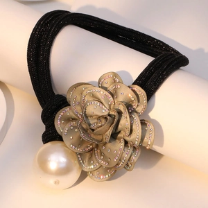 Close-up of champagne fabric flower hair tie with sparkling crystals and large faux pearl