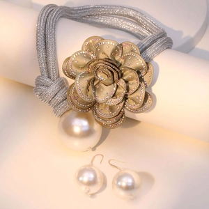 Detail of a braided necklace with a sparkling diamond flower and pearl drop pendant