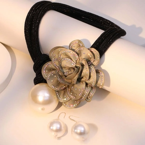 Detail of floral necklace and pearl earrings set on white display stand with soft lighting
