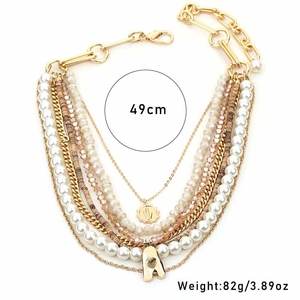 Detail of multilayer necklace featuring white pearls, brown beads, and gold letter A pendant