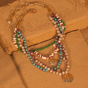 Collier multicouche bohème avec perles de cristal et pendentif cœur sur brique beige
