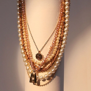Layered beaded necklace with pearls, wooden beads, and sunburst medal with letter A pendant