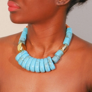 Close-up of chunky sky blue resin bead necklace with irregular gold accents on model