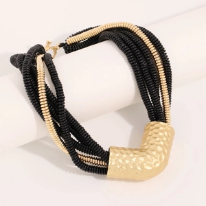 Detail of layered bohemian necklace with black textured beads and hammered gold tube