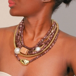 Détail du collier bohème multicouche avec perles mauves et pendentif doré irrégulier