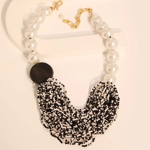 Detail of bohemian multilayer necklace with pearls and black beads on white stand