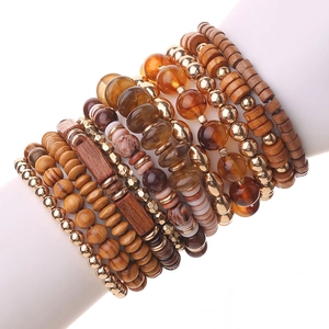 Bohemian stacked beaded bracelet set with brown wood and metallic beads on a white hand mold