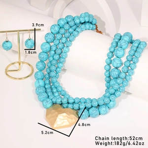 Détail d'un collier de perles turquoise à plusieurs rangs avec pendentif cœur doré et boucles