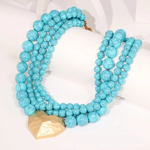 Détail du collier de perles turquoise multicouche avec un pendentif cœur martelé doré