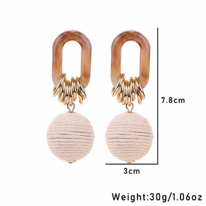 Detail view of handmade drop earrings with amber resin and beige woven spheres, 7.8cm height