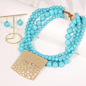 Détail d'un collier de perles turquoise à plusieurs rangs avec pendentif doré et boucles