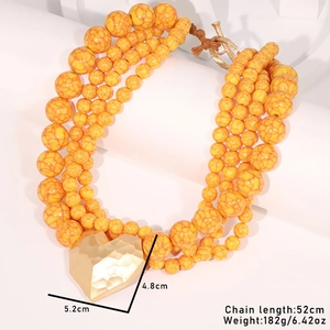 Detail of multi-layer beaded necklace with yellow beads and hammered gold heart pendant
