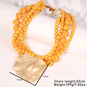 Detail of yellow acrylic beaded necklace with irregular gold heart pendant and size specs