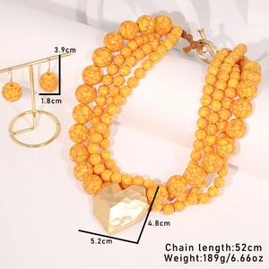 Detail of multilayer yellow beaded necklace with large golden hammered heart pendant