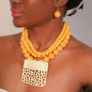 Detail of layered beaded necklace with marble texture beads and hammered gold square charm