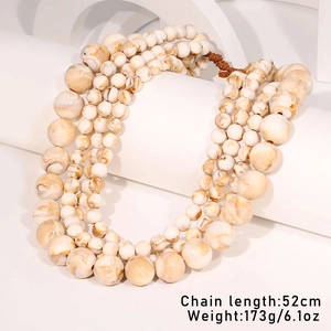 Detailed view of triple-layered beaded necklace with cream marble texture on white stands