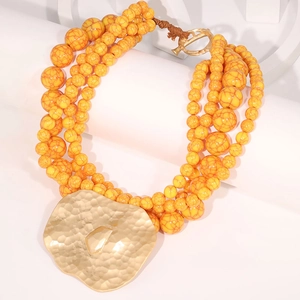 Multilayer yellow beaded necklace with irregular gold heart pendant on white geometric blocks
