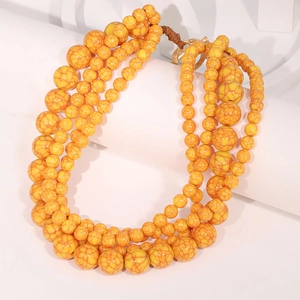 Detail of four-strand yellow beaded necklace with irregular resin beads and metal clasp