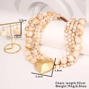 Detail of layered marble bead necklace with large gold heart pendant and drop earrings