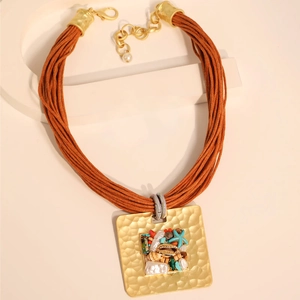 Détail d'un collier bohème avec cordons multicouches et pendentif carré en pierre
