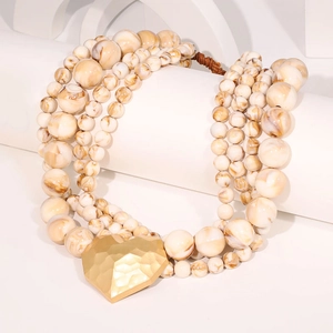 Macro view of multi-layer beaded necklace featuring resin beads and gold heart pendant