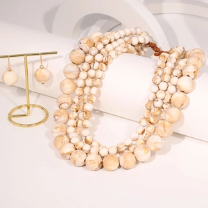 Macro detail of layered beaded necklace set with marble texture and golden jewelry stand