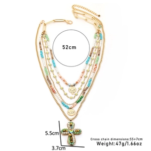 Détail d'un collier bohème multicouche avec perles, marguerites et grand pendentif en croix
