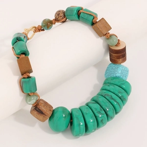 Detail of woven necklace with turquoise beads, wooden blocks, and golden clasp