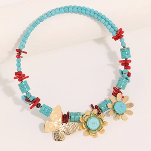 Handmade turquoise beaded necklace with gold butterfly and floral charms on white background