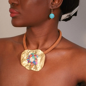 Ethnic necklace with colorful stones and hammered gold metal pendant on a model