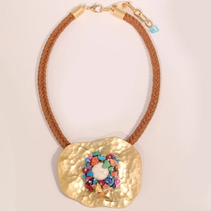 Macro shot of bohemian necklace with textured gold disc and colorful natural stones