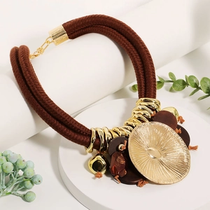Close-up of bohemian leaf pendant necklace with woven cord and golden metal rings