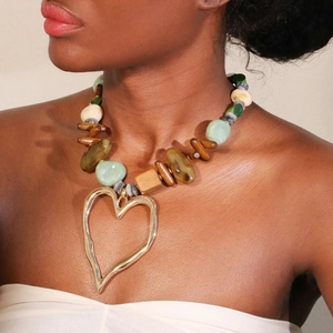 Collier bohème en perles de pierre et bois avec un grand pendentif cœur doré sur un mannequin