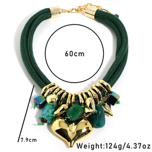 Detailed view of layered green rope necklace with large gold heart pendant and turquoise charms