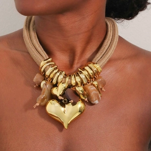 Macro detail of multi-strand rope necklace with polished gold heart pendant and marble beads