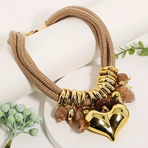 Detail of bohemian layered necklace with large gold heart pendant and marble beads
