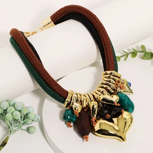 Detail of bohemian layered rope necklace with a large golden heart pendant and resin beads