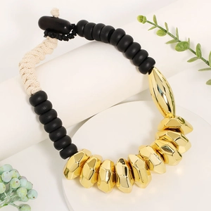 Collier bohème à perles dorées et noires avec corde tressée sur un présentoir blanc