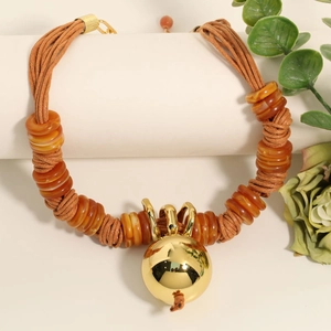 Bohemian wax rope necklace with amber resin beads and a large gold metal ball pendant