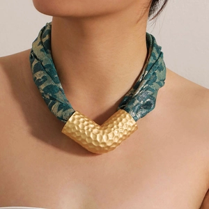 Detail of hammer-textured V-shaped gold pendant on leopard print fabric choker necklace