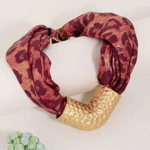Bohemian leopard fabric necklace with hammered gold metal pendant on display