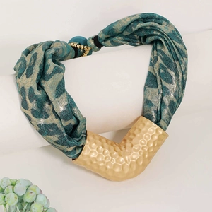 Detail of fabric scarf necklace featuring blue leopard print and hammered gold metal tube