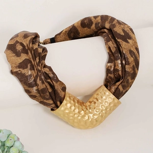 Close-up of leopard print fabric and hammered gold curved metal on a chic necklace